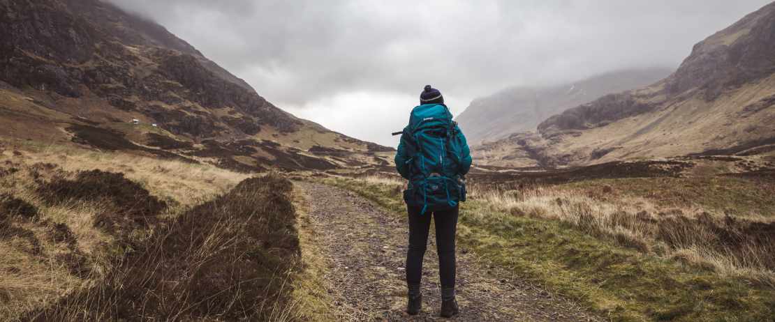 Frau auf einer Trekking-Tour mit Rucksack in den Schottische Highlands